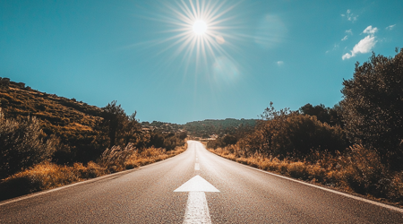 Een foto van een snelweg met een lange witte pijl die naar de verte wijst op de weg.